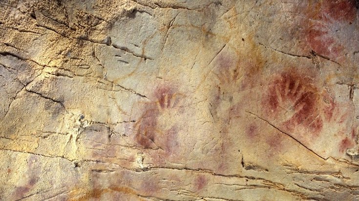 Diese Malerei in der spanischen El Castillo Höhle ist mit 42 000 Jahren die älteste in Europa. Die rötliche Farbe der Handabdrücke haben die Frühmenschen wahrscheinlich als Sonnenschutz gegen zu intensive UV-Strahlung genutzt | Bildquelle: Paul Pet Rötliche Malereien auf einer Felswand