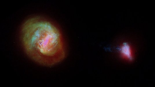Zwei Galaxien nebeneinander auf dunklem Hintergrund. Links die Große Magellansche Wolke und rechts die deutlich kleinere Kleine Magellansche Wolke.