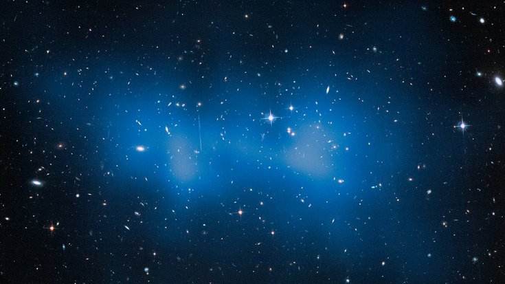 Verteilung von Dunkler Materie im Galaxienhaufen ACT-CL J0102-4915 | Bildquelle: NASA/ESA/M.J. Jee Auf dem Bild sind vor dunklem Hintergrund viele leuchtende Galaxien zu erkennen, überlagert von einer wolkenartigen Struktur.